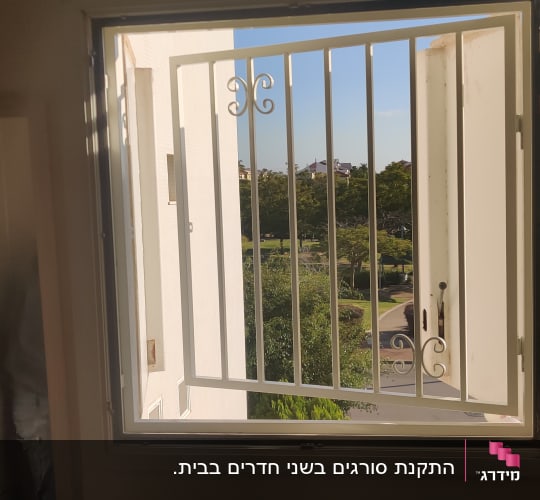 חלון פתוח עם סורג מתכת לבן